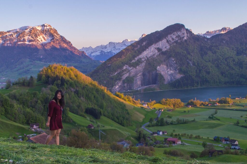 Traveler in red dress in front of Swiss mountains near Lucerne at sunset