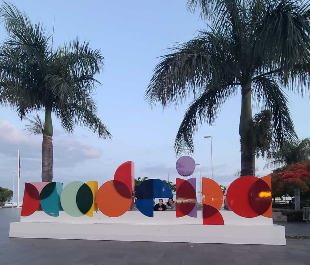 Two people looking through a large "Madeira" sign