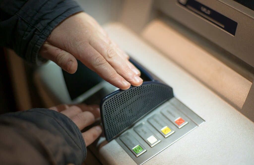 Man covering pin code at an ATM