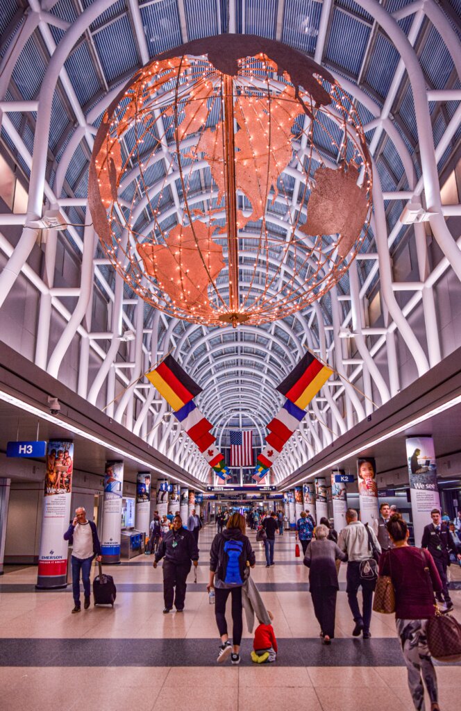 Airport with decorations like flags and a globe and travellers walking down 