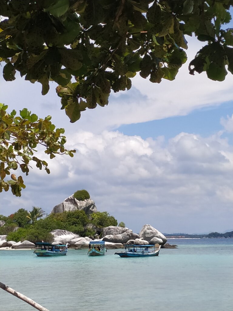 White limestone rocks with boats on light blue water in Belitung Island Indonesia