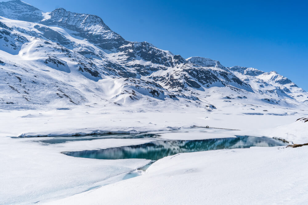 Bernina Express train ride Switzerland views over a snowy lake.