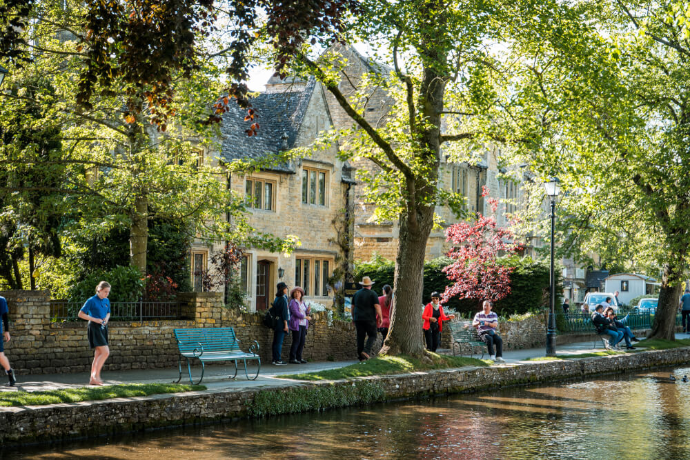 A photo of tourists relaxing by the water in Bourton on the Water in England.