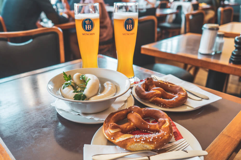 Traditional Bavarian breakfast consisting of white sausages, pretzels and wheat beer.