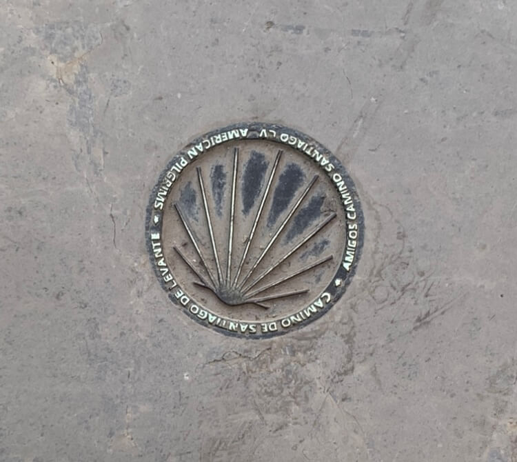 A scallop shell in the ground,  pointing the way to Santiago de Compostela