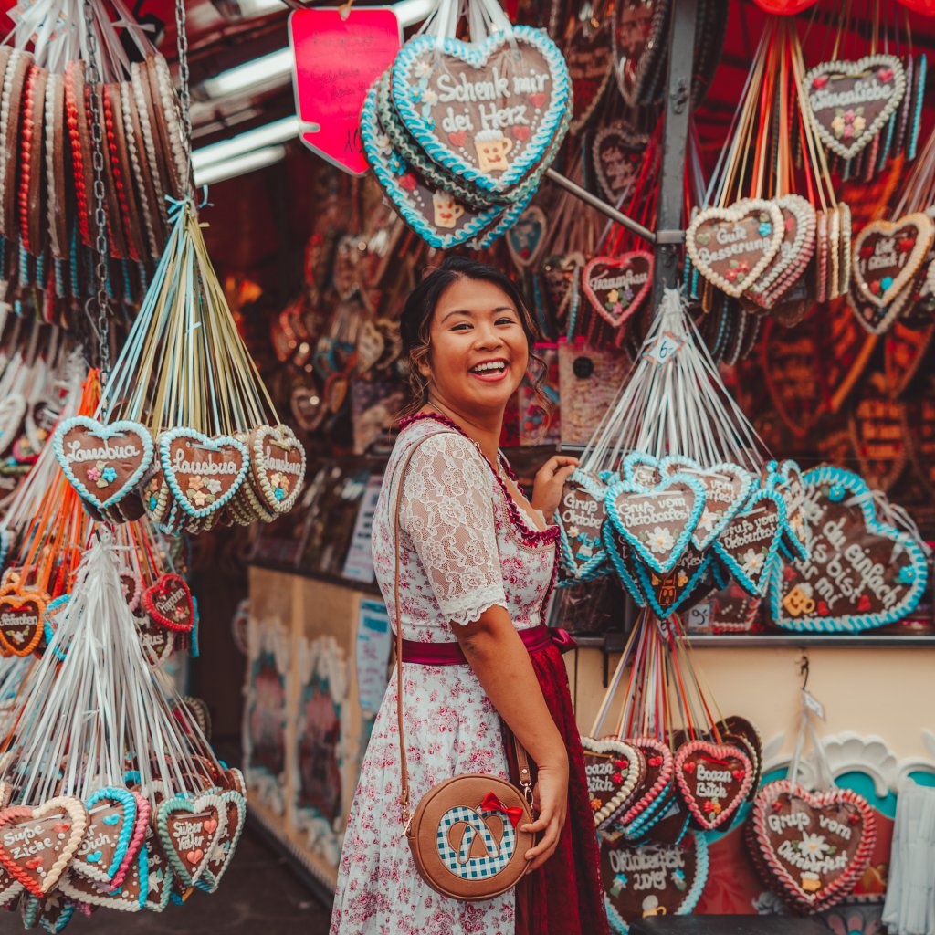 Christina Guan wearing a dirndl looking at gingerbread hearts at Oktoberfest in Munich, Germany