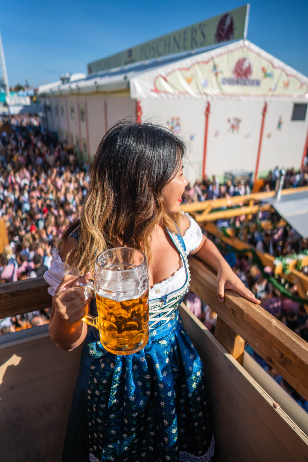 Christina Guan wearing a dirndl and holding a beer at Oktoberfest in Munich, Germany