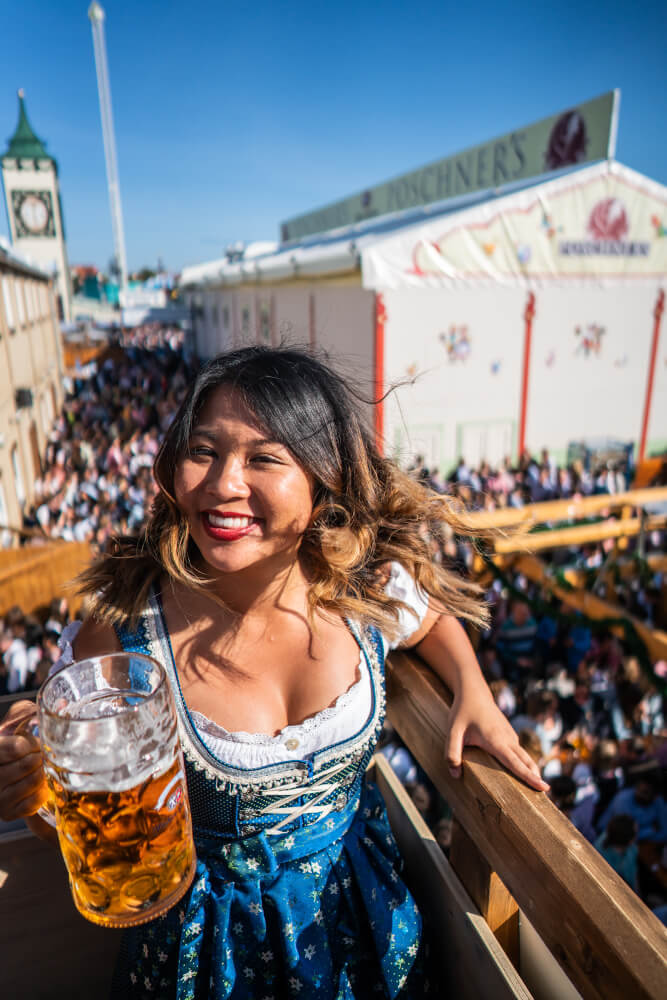 Christina Guan in a dirndl holding an Oktoberfest beer.