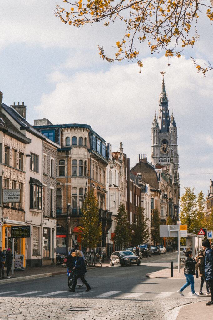 Couple walking across the street in Ghent, Belgium with the Belfry in the background