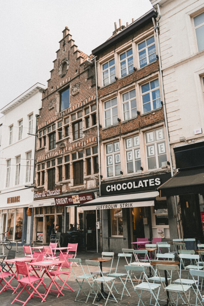 Colourful chairs in front of Ghent storefronts selling chocolate