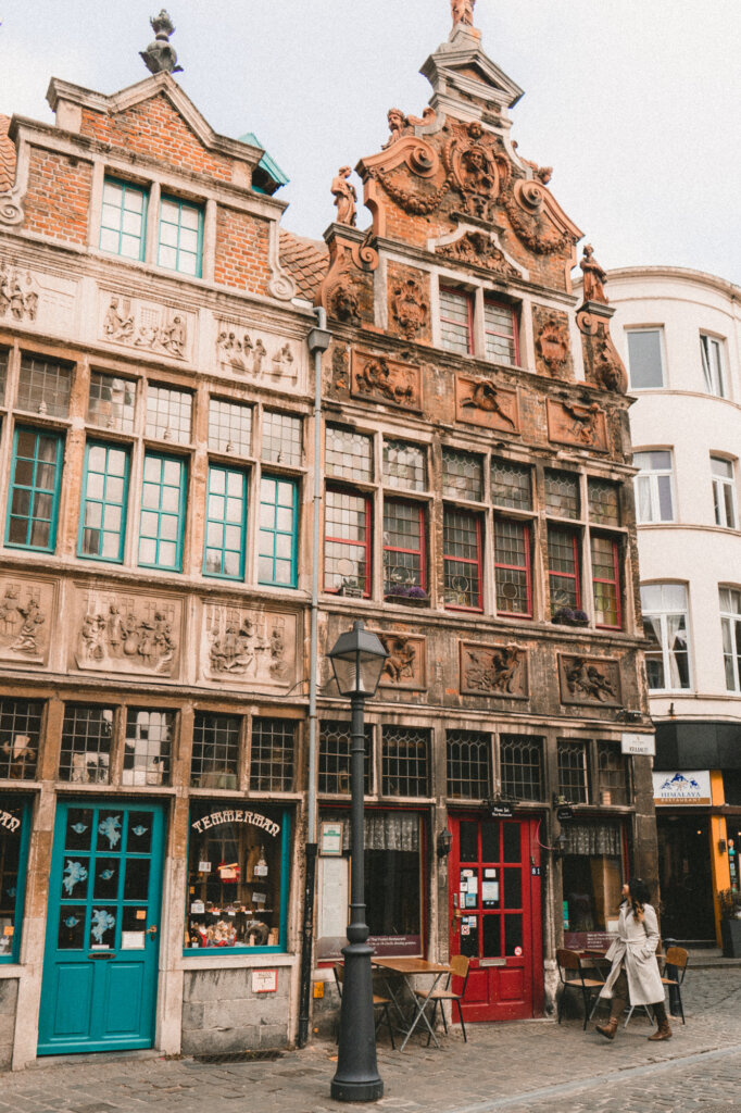 Travel blogger walking in front of beautiful storefronts in Ghent