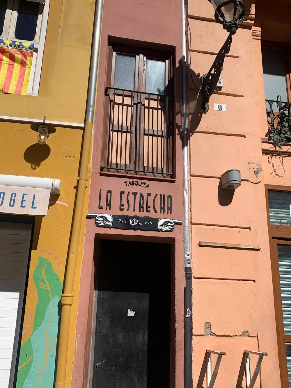 A very narrow pink house with a sign that says "La Estrecha"