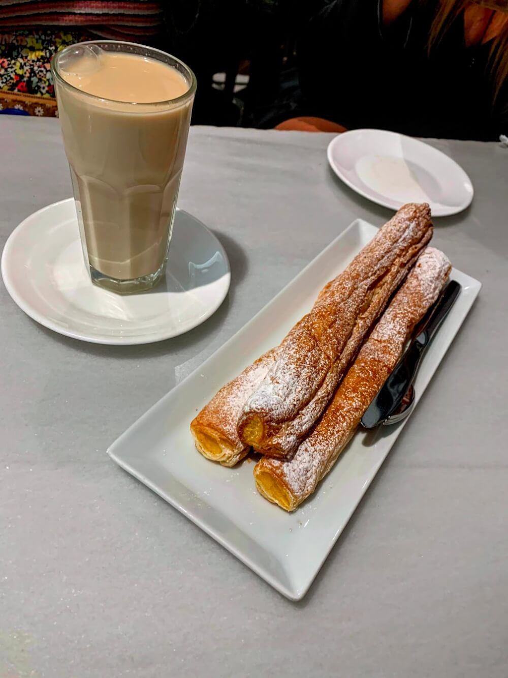 A tan drink (horchata) and a plate of three long circular pastries