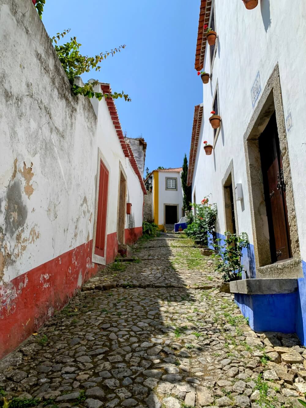 An narrow uphill pedestrian street with white houses on each side.