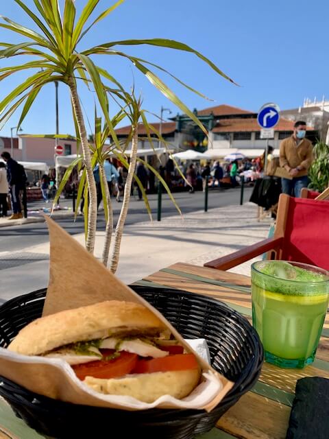 A cheese and tomato sandwich and mint lemonade at an outdoor restaurant.