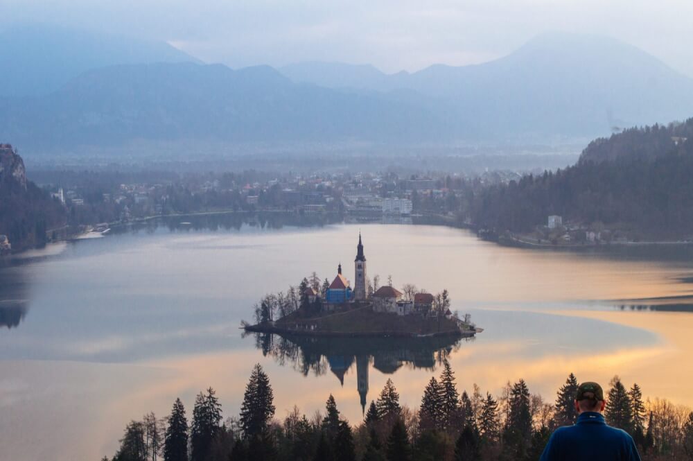 How to get the BEST view of Lake Bled, Slovenia at sunrise. This guide shows you how to hike to this gorgeous viewpoint of Lake Bled and gives you practical advice on how to find the trail head and more!