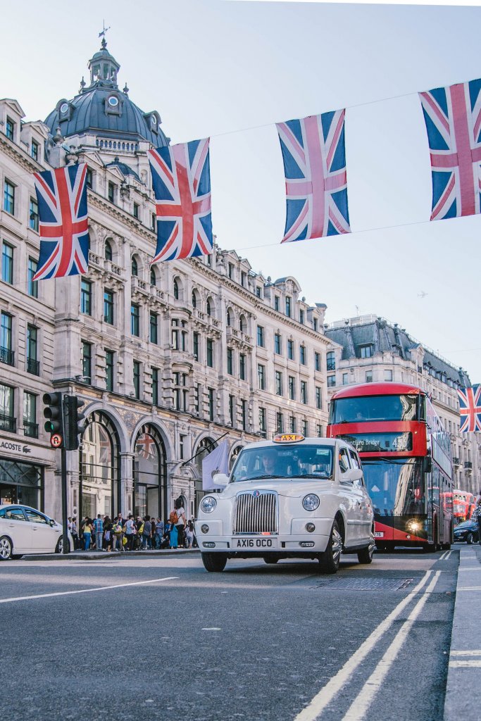 British flags in London with cars and buses on the road