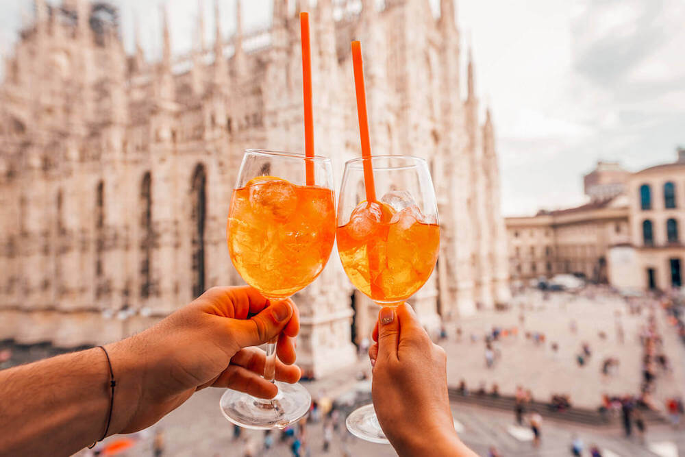 Aperol spritz cheersing in front of the Duomo in Milan