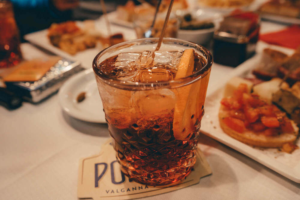 A cold Negroni with plates of delicious food