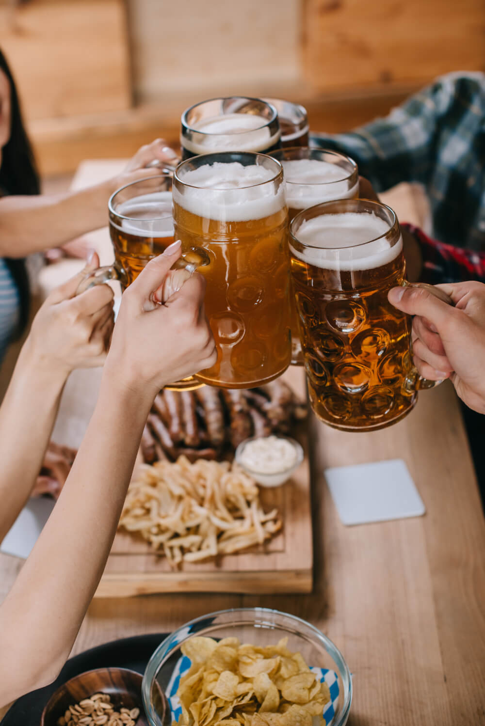 Beers cheersing at an Oktoberfest party at home with snacks.