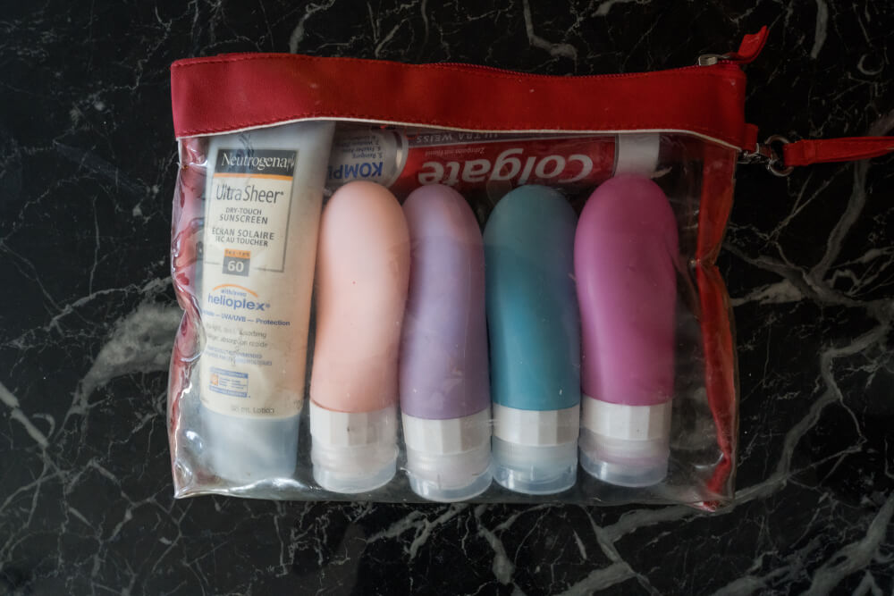 Travel toiletries clear bag filled with toiletries in pastel colored bottles