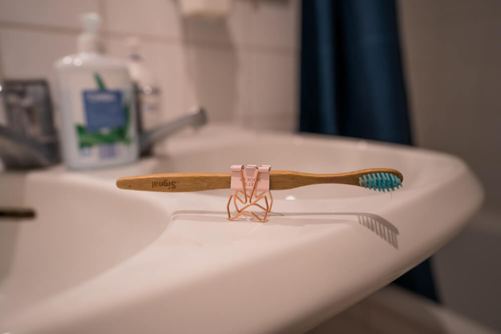 Toothbrush held up by a money clip on a sink