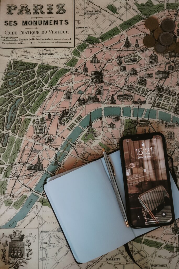 Tourist map of Paris with a notebook on top and a phone