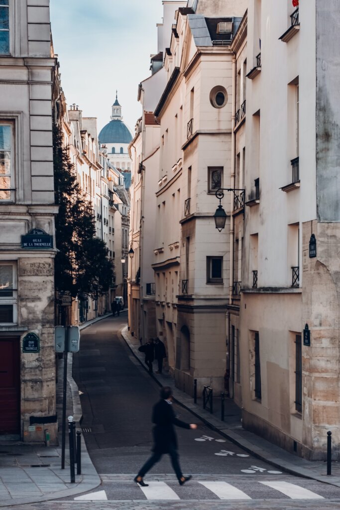 Man walking across the street in a narrow Parisian street