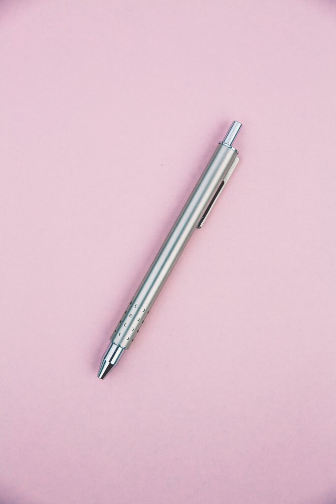 A silver pen on a pink background