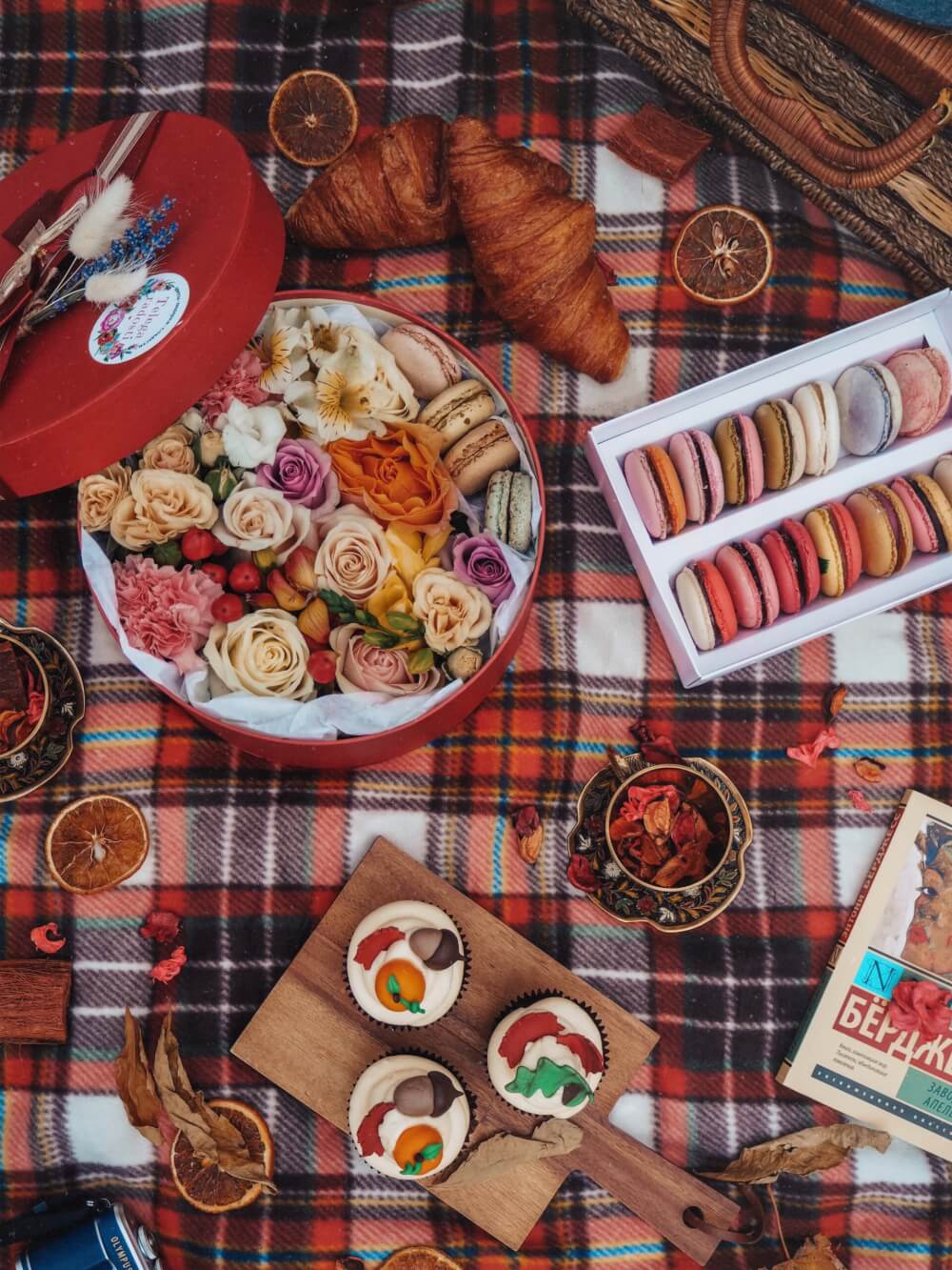 Picnic spread with cupcakes and a baguette on a checkered blanket