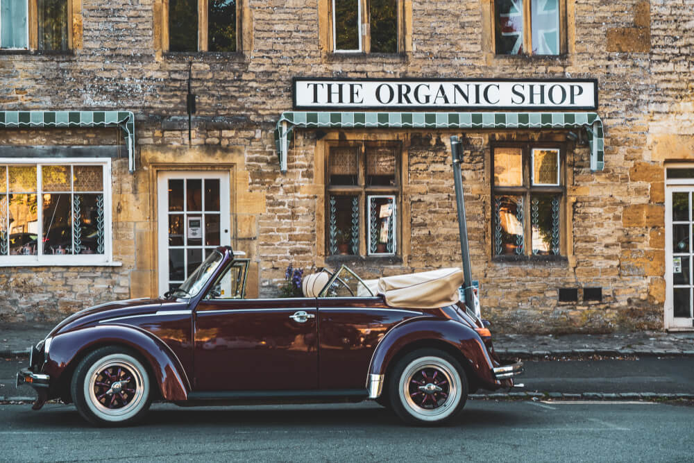 A cute vintage car parked in front of a shop in Stow on the Wold