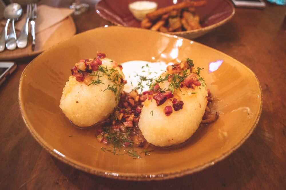 Cepelinai potato dumplings on a plate with sour cream and bacon
