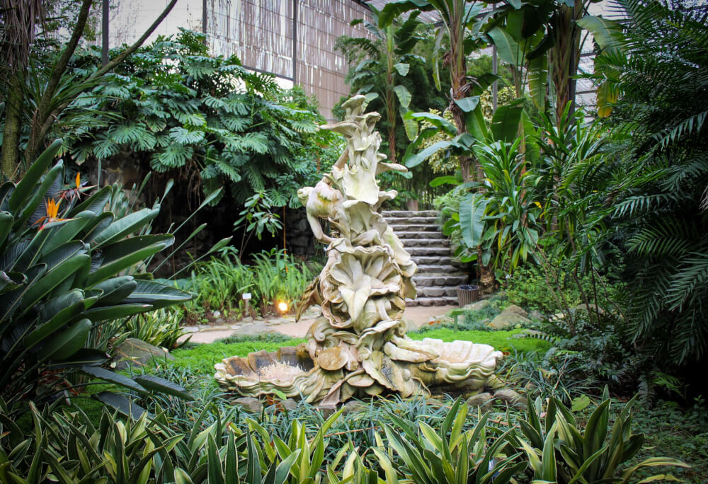 A tropical indoor garden with a white statue in the center