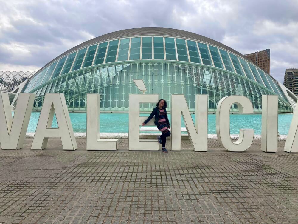 Woman posing in front of a sign that says "Valencia" 
