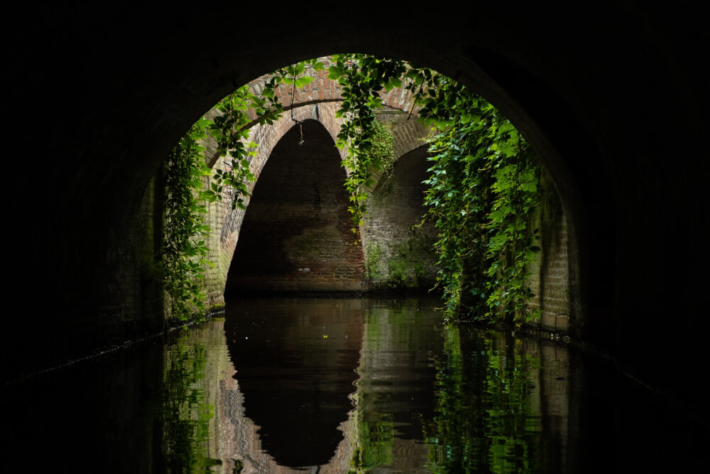 Brick arches over a canal with ivy hanging down in Den Bosch, the Netherlands.