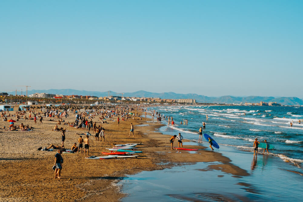 Sunny beach filled with surfers, swimmers, and families having fun