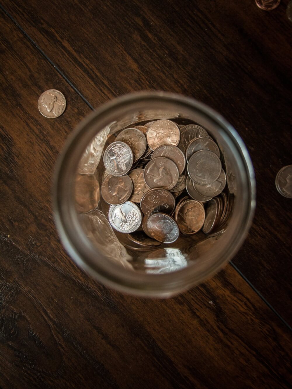 Coins in a jar on a brown wooden table