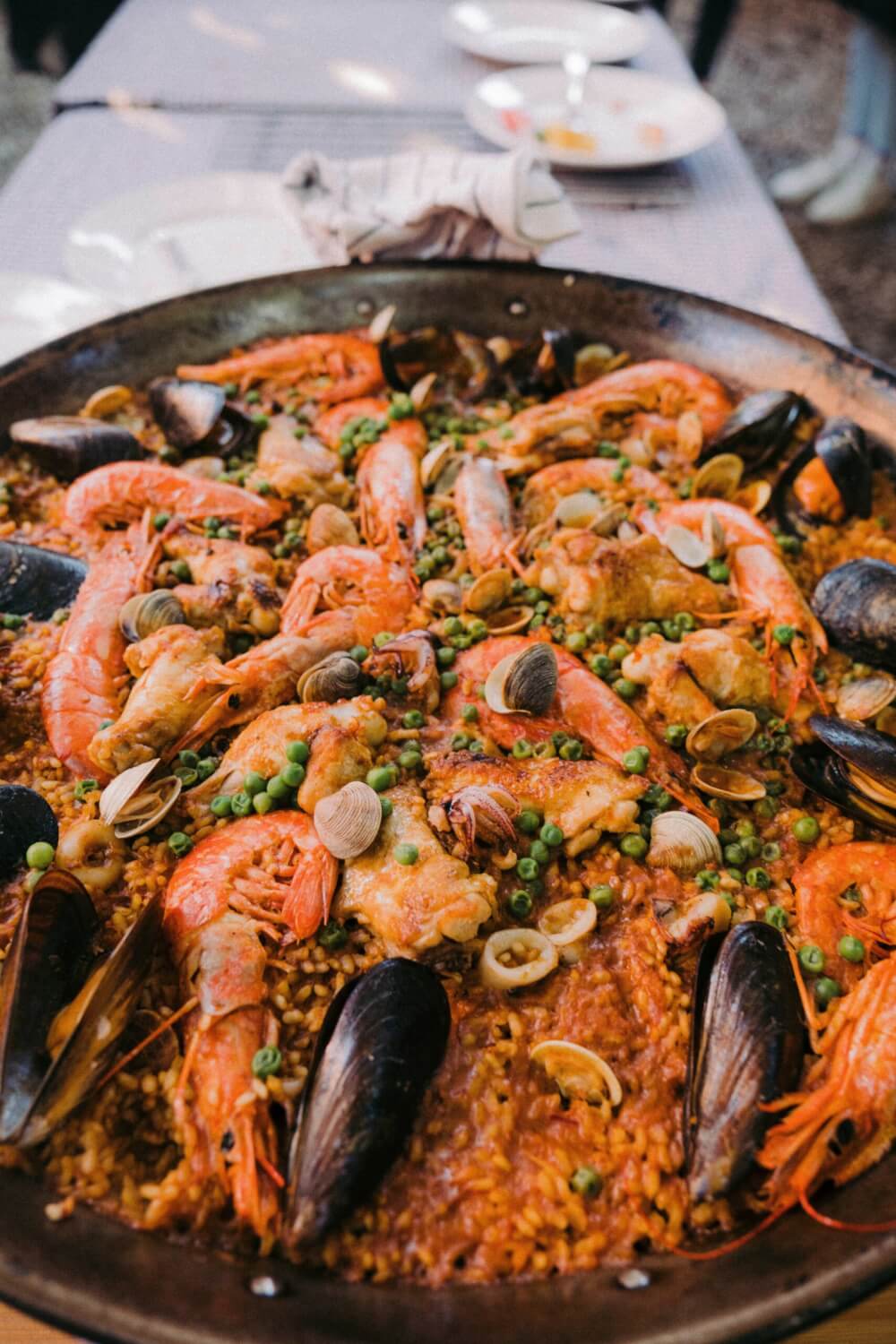 A plate of paella, with prawns, clams, mussels, and peas.