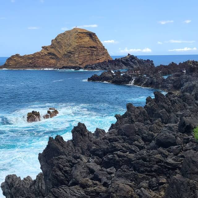 Sharp rocks next to blue ocean waves 