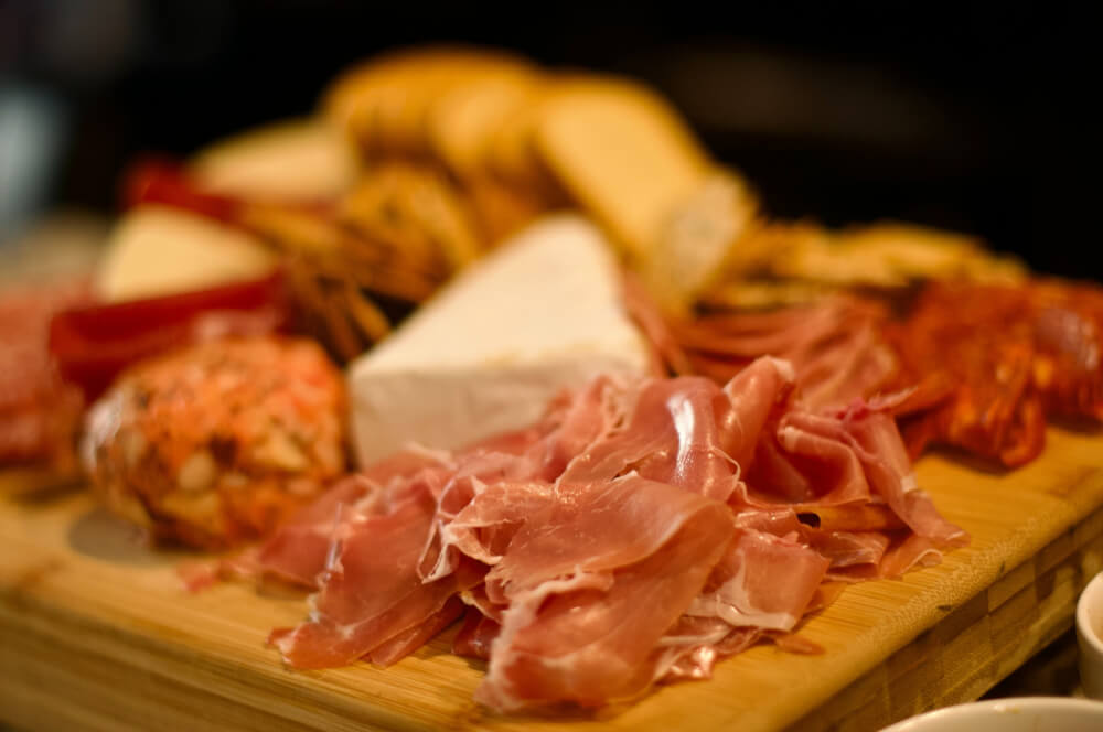 A charcuterie board with cheese, crackers, and ham.  