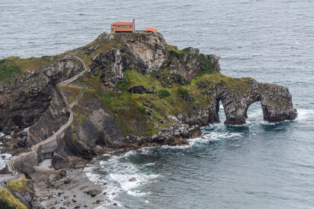A single house sits on a steep cliff by the ocean