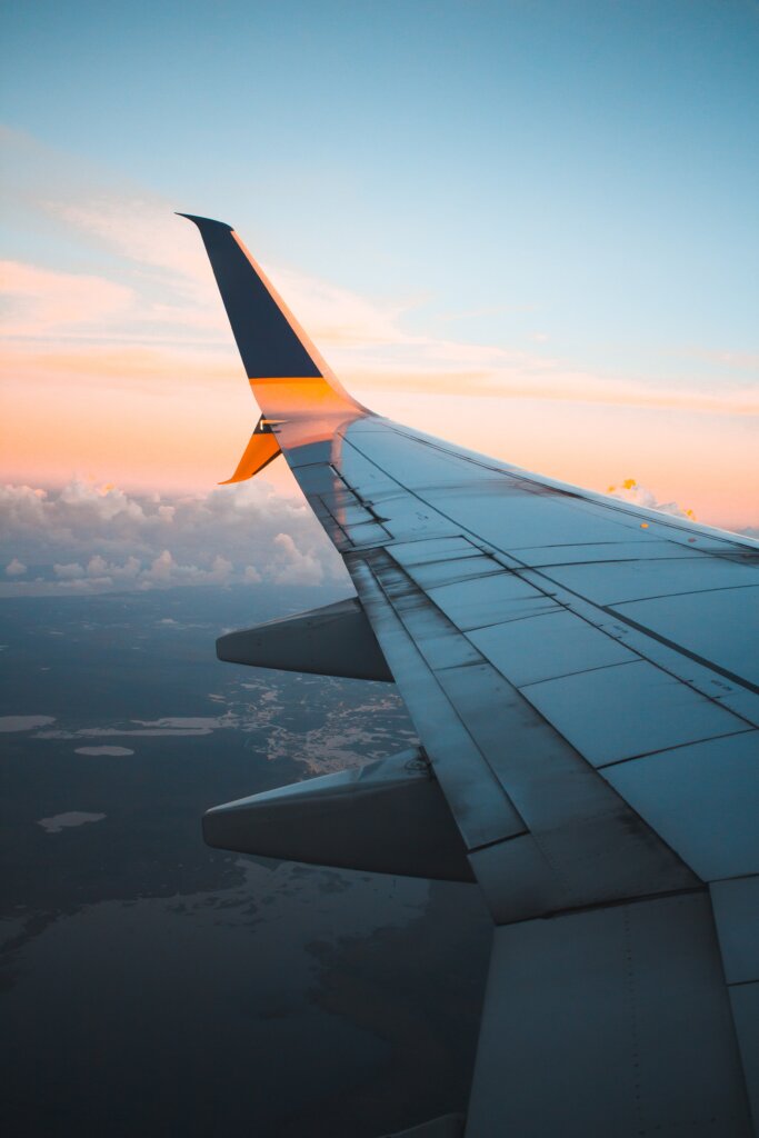 Vista do lado de fora da janela de um avião ao pôr do sol