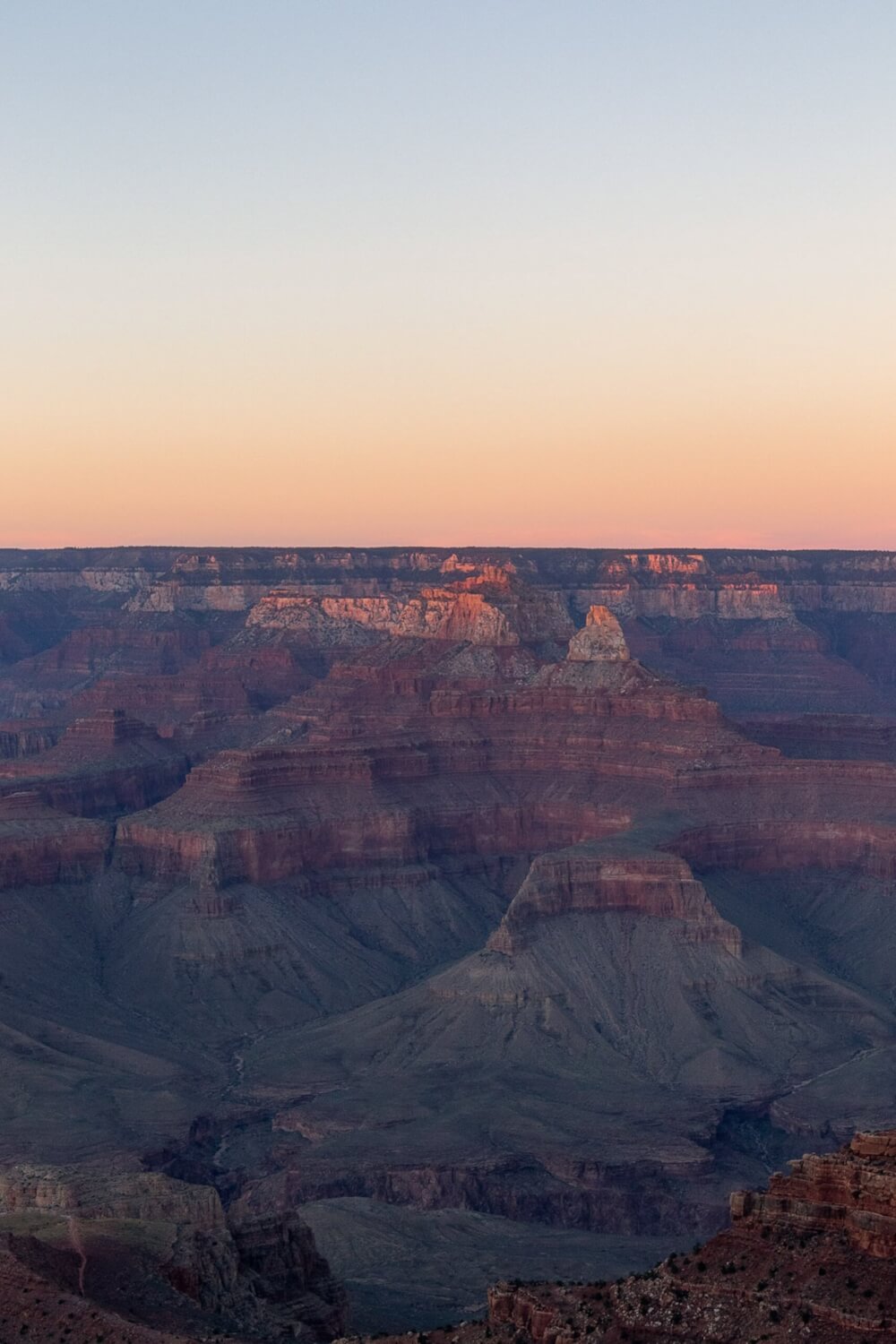 A view of the grand canyon at dusk, showing the various layers of rock.