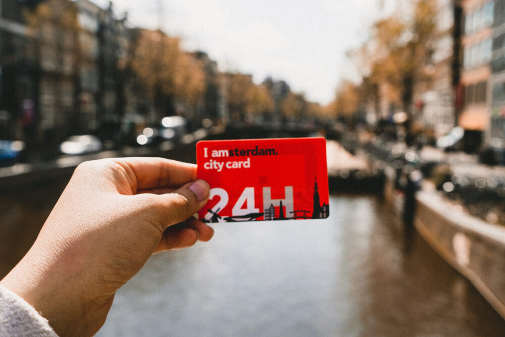 Amsterdam card being held up over a canal