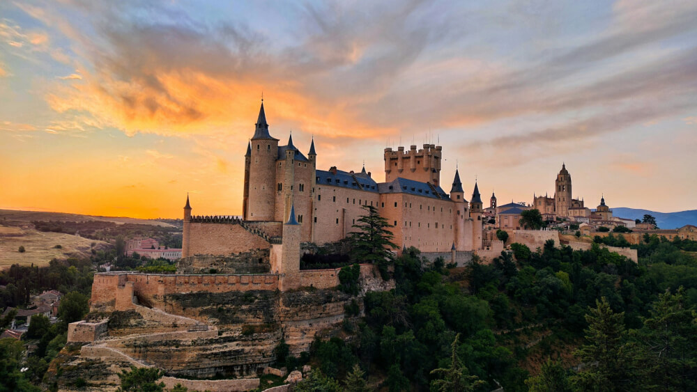 A castle in Segovia, Spain, on the top of a hill at sunset