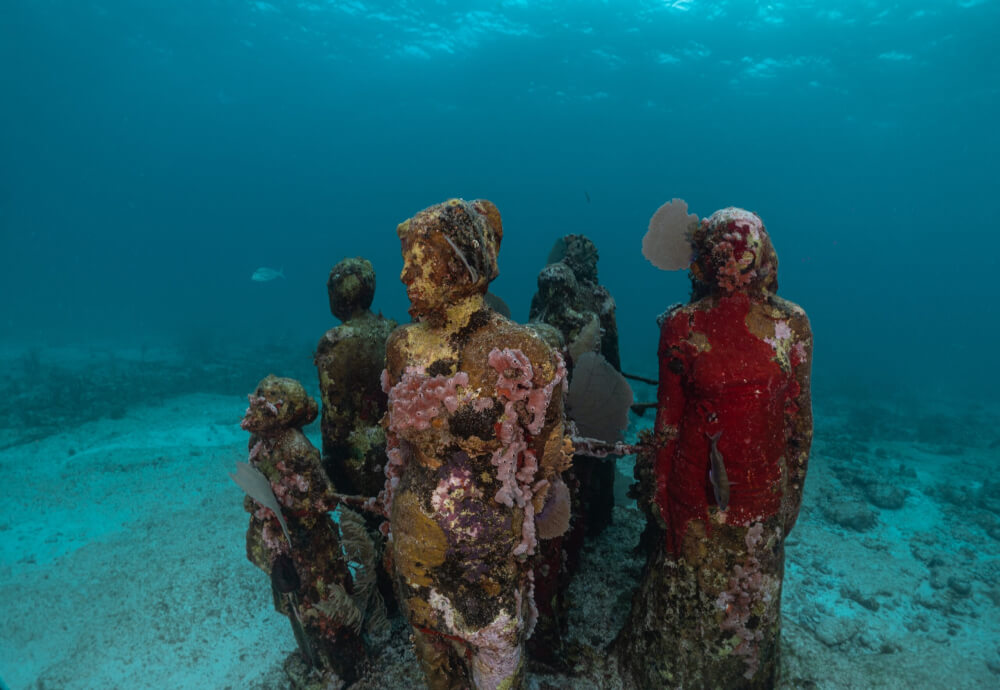 Underwater statues that are growing barnacles and coral