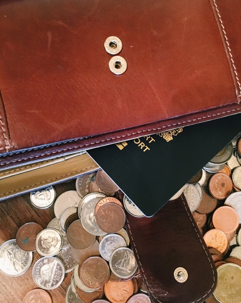 Wallet and passport on top of a pile of coins