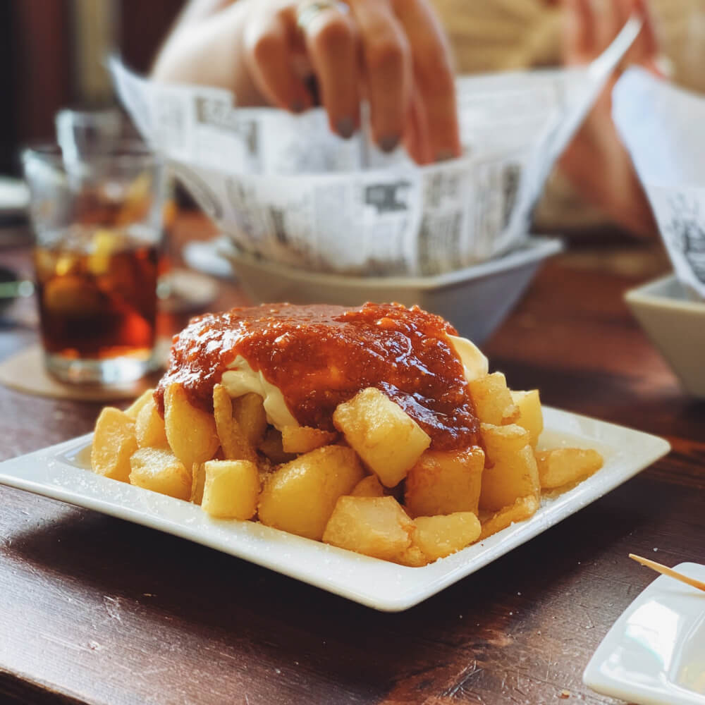 A plate of fried potatoes, covered in spicy red sauce.