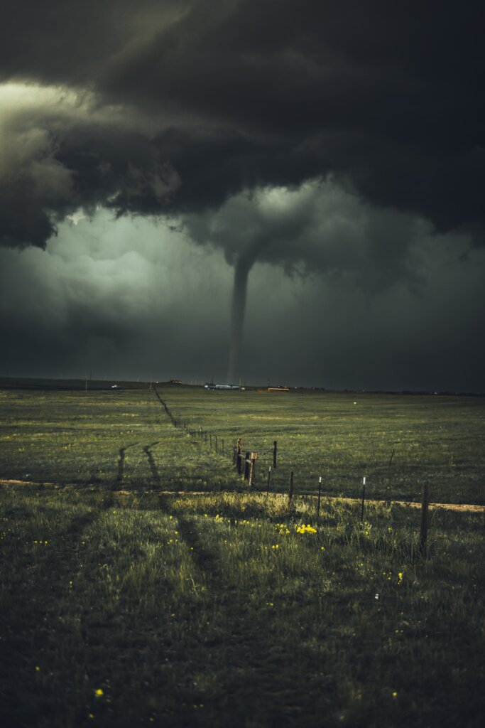 A tornado touching down in the distance, connecting earth to sky. 