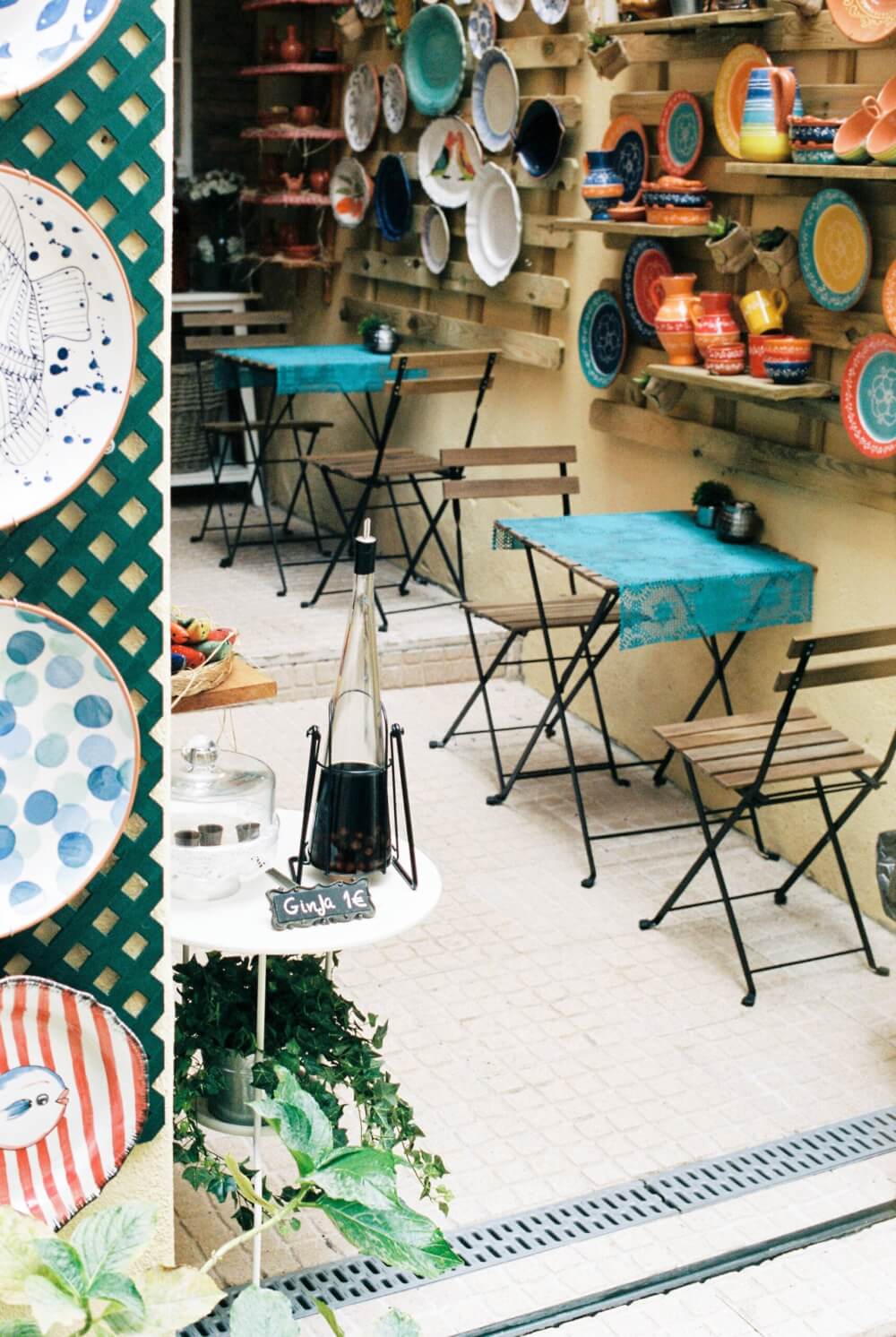 A cafe with hand-painted ceramics hanging on the walls and a bottle of Ginja for sale